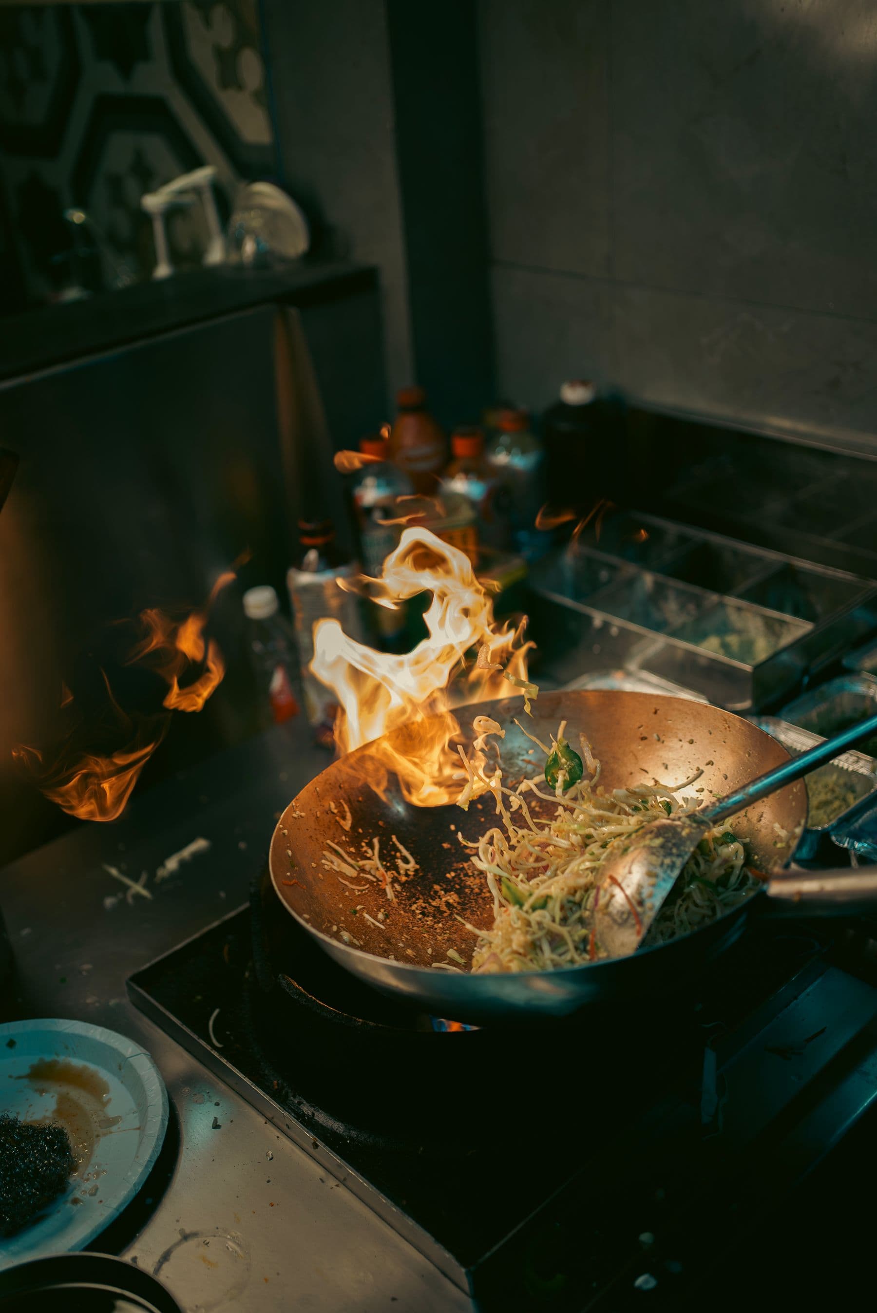 Nudeln werden über einer offenen Flamme im Wok gebraten